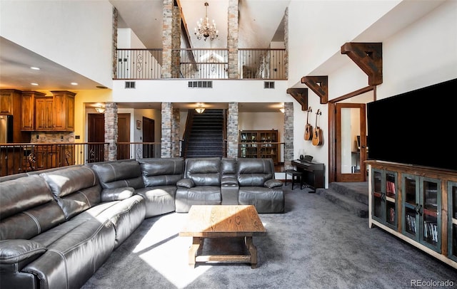 carpeted living area with a notable chandelier, visible vents, ornate columns, and high vaulted ceiling