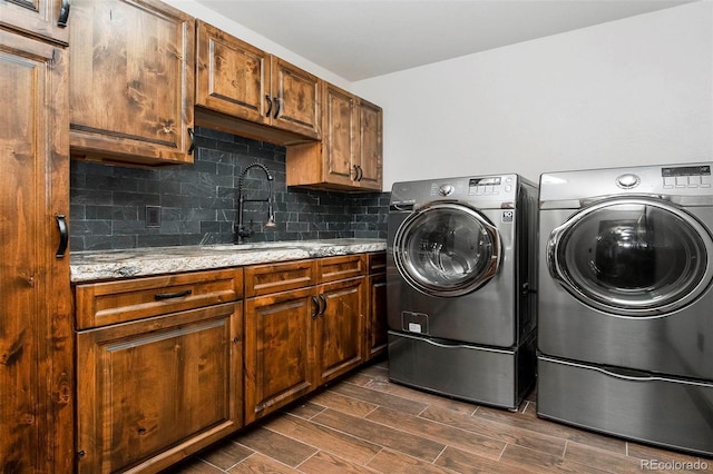 laundry area with cabinet space, independent washer and dryer, dark wood-type flooring, and a sink