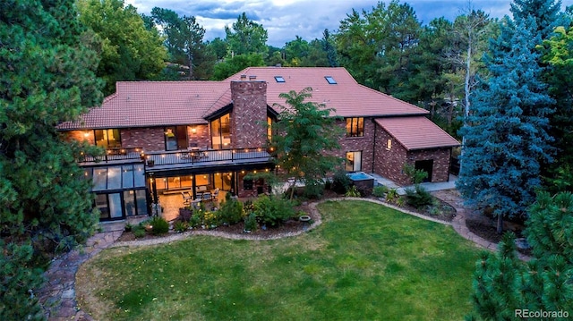 back of property with a patio, a yard, a chimney, a deck, and brick siding