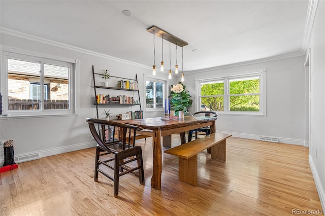 dining area with ornamental molding and light wood-type flooring