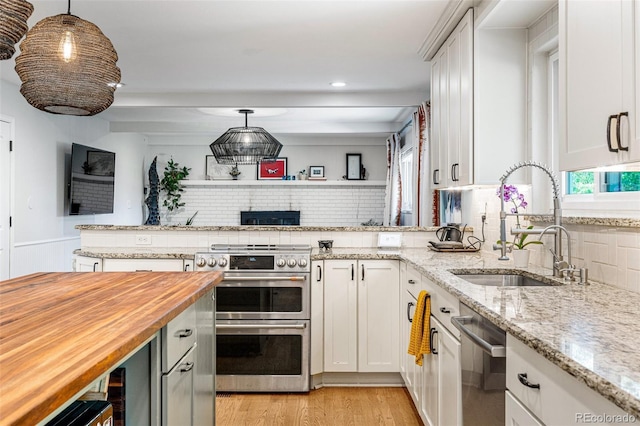 kitchen featuring hanging light fixtures, sink, white cabinets, and butcher block countertops