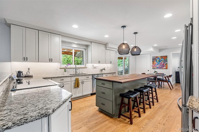 kitchen with a breakfast bar, white cabinetry, wooden counters, a center island, and stainless steel appliances