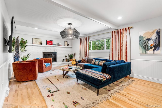 living room with a brick fireplace, hardwood / wood-style floors, and beam ceiling