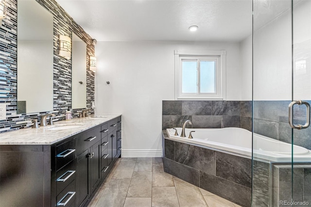 bathroom with vanity, tiled tub, tile patterned flooring, and backsplash