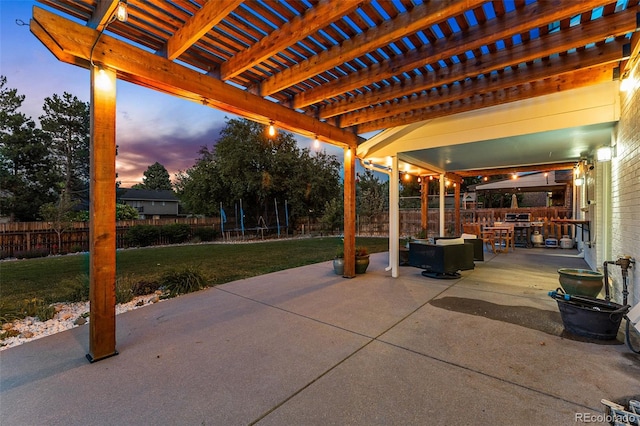 patio terrace at dusk with a trampoline, a yard, and a pergola