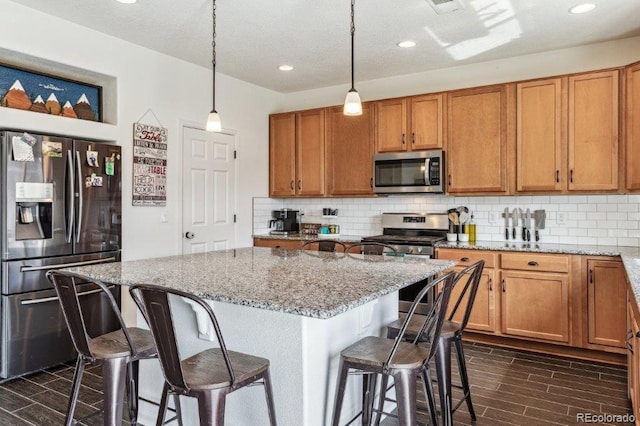 kitchen with decorative backsplash, a breakfast bar area, appliances with stainless steel finishes, and wood finish floors