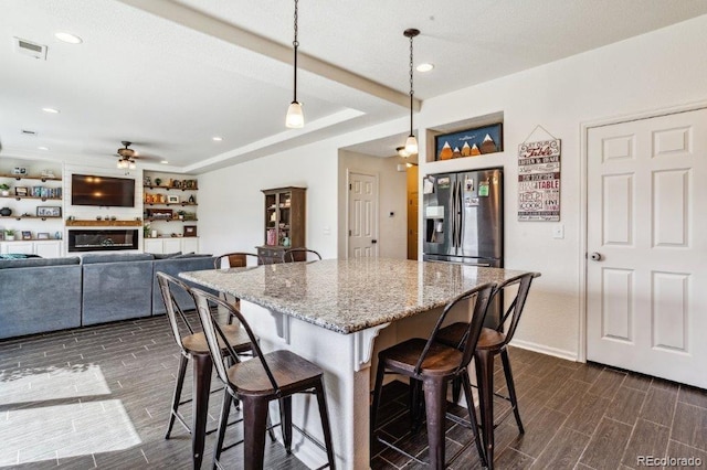 kitchen featuring visible vents, wood finish floors, light stone countertops, a breakfast bar, and stainless steel refrigerator with ice dispenser