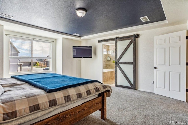 bedroom with a barn door, a raised ceiling, and visible vents