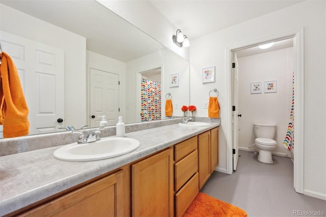 bathroom with double vanity, toilet, baseboards, and a sink