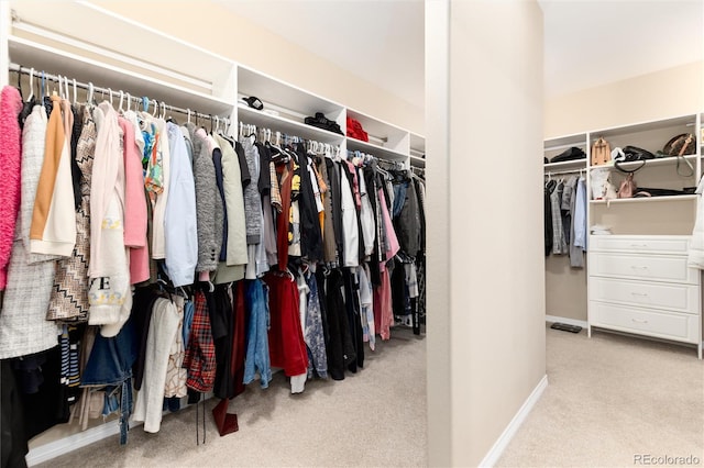 walk in closet with light carpet