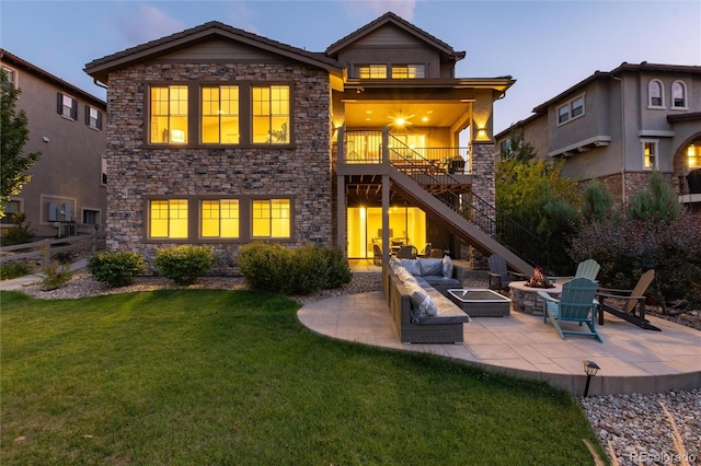 back house at dusk with a yard, an outdoor living space with a fire pit, and a patio area