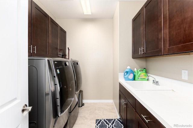 laundry area with washer and clothes dryer, cabinets, sink, and light tile patterned flooring