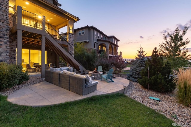 patio terrace at dusk with a lawn and an outdoor living space with a fire pit