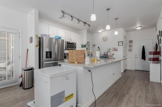 9185 Wilde Ln Unit 101, Parker, CO 80134 - kitchen featuring appliances with stainless steel finishes, light wood-type flooring, white cabinetry, and light countertops