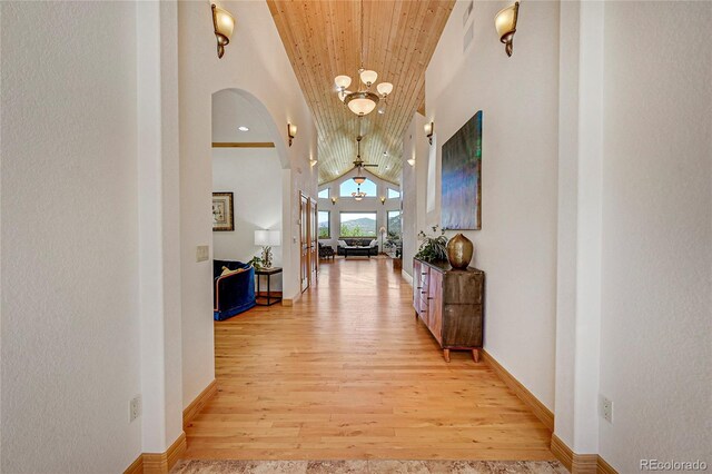 hall with light hardwood / wood-style flooring, high vaulted ceiling, wooden ceiling, and a notable chandelier