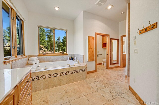 bathroom featuring a relaxing tiled tub and toilet