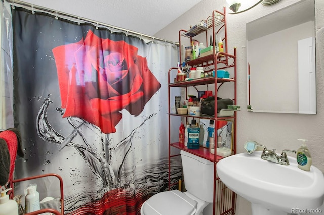 bathroom featuring walk in shower, toilet, and sink