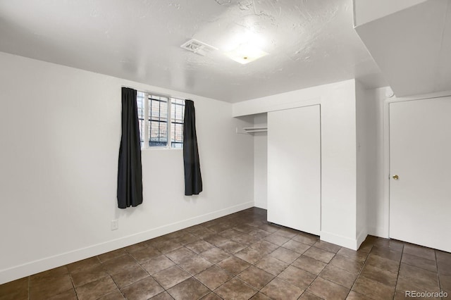 unfurnished bedroom featuring dark tile patterned floors, a textured ceiling, and a closet