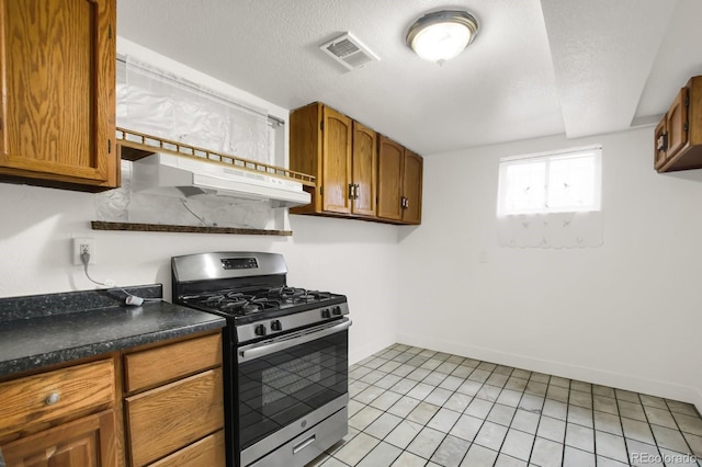 kitchen with stainless steel gas range oven, light tile patterned flooring, and a textured ceiling