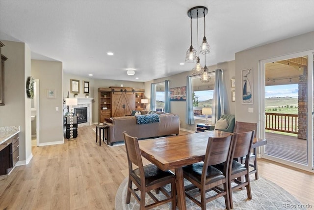 17102 W 85th Pl, Arvada, CO 80007 - dining area featuring a glass covered fireplace, light wood-style floors, baseboards, and recessed lighting
