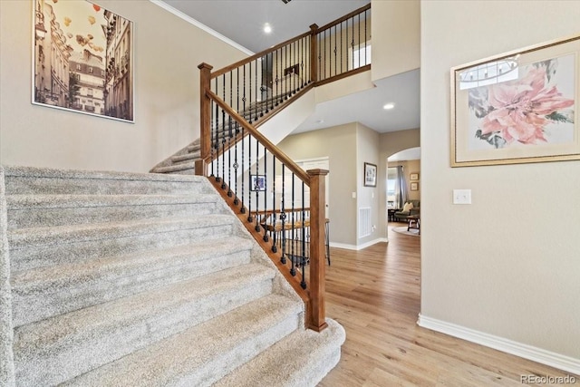 17102 W 85th Pl, Arvada, CO 80007 - staircase featuring arched walkways, baseboards, wood finished floors, ornamental molding, and a high ceiling