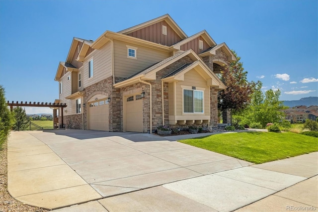 17102 W 85th Pl, Arvada, CO 80007 - view of front of house with board and batten siding, stone siding, concrete driveway, a front lawn, and a garage