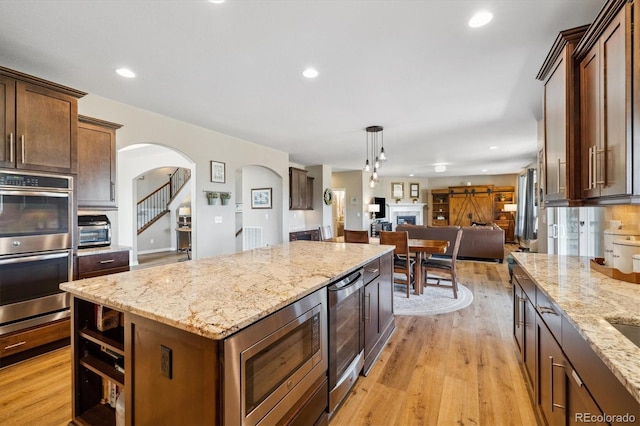 17102 W 85th Pl, Arvada, CO 80007 - kitchen featuring stainless steel appliances, beverage cooler, arched walkways, open floor plan, and a center island