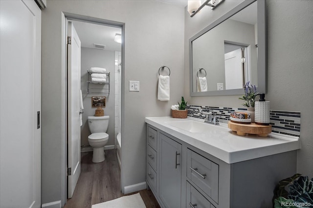 bathroom featuring visible vents, vanity, toilet, and decorative backsplash