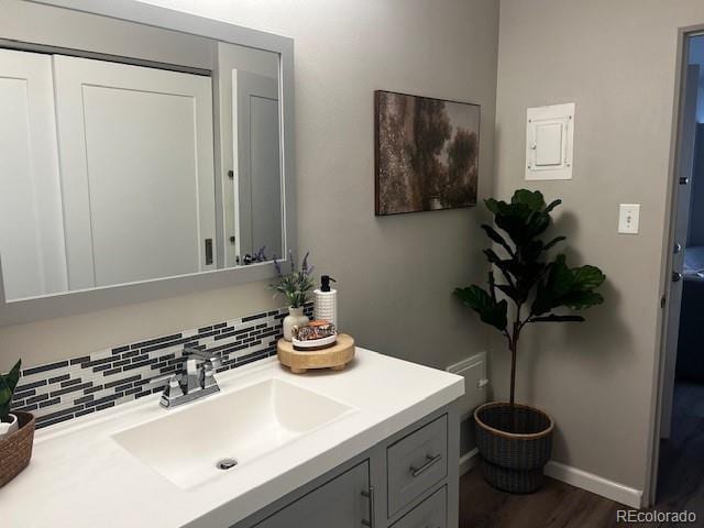 bathroom featuring wood finished floors, backsplash, vanity, and baseboards