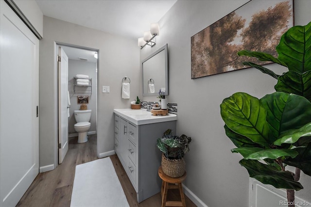 bathroom with visible vents, baseboards, toilet, wood finished floors, and vanity