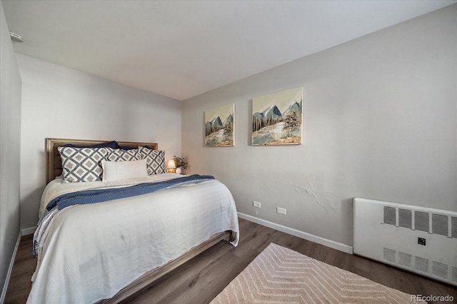 bedroom featuring radiator heating unit, baseboards, and wood finished floors