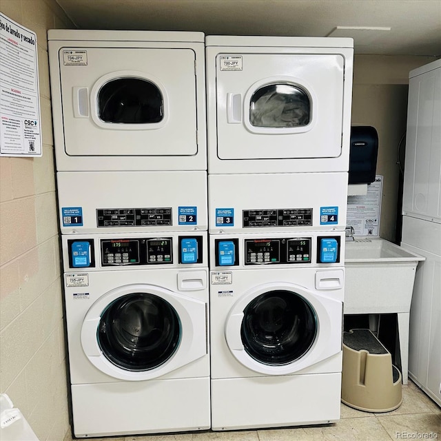 community laundry room with concrete block wall, stacked washer / dryer, and independent washer and dryer