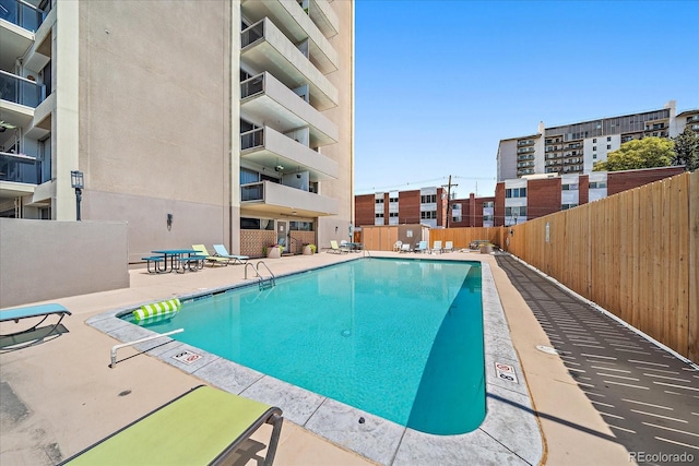 community pool with a patio area and fence