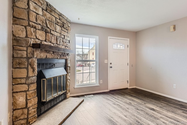 entryway with baseboards, a fireplace, wood finished floors, and a textured ceiling