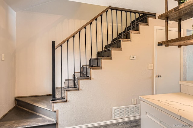 staircase with a textured wall and visible vents