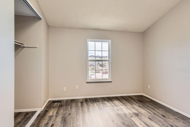 interior space featuring visible vents, a textured ceiling, baseboards, and wood finished floors