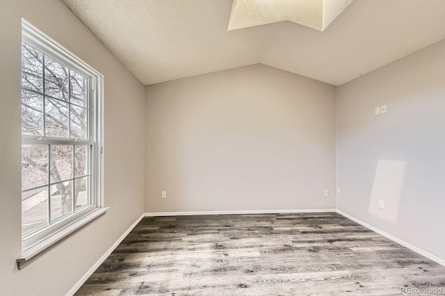 spare room featuring baseboards, lofted ceiling, a textured ceiling, and wood finished floors
