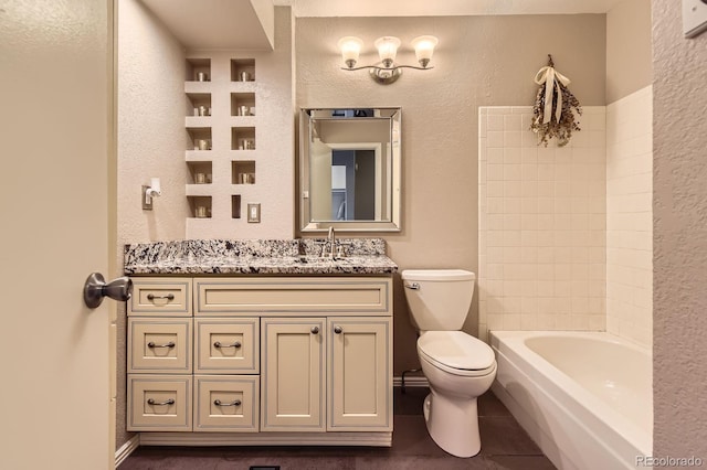 bathroom featuring a bathing tub, toilet, vanity, and a textured wall