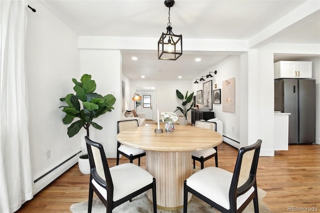 dining room with baseboard heating and light hardwood / wood-style flooring