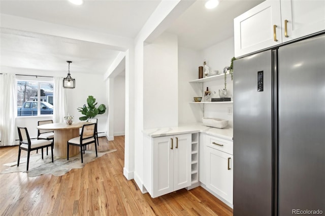 kitchen with white cabinetry, pendant lighting, stainless steel fridge, and light wood-type flooring