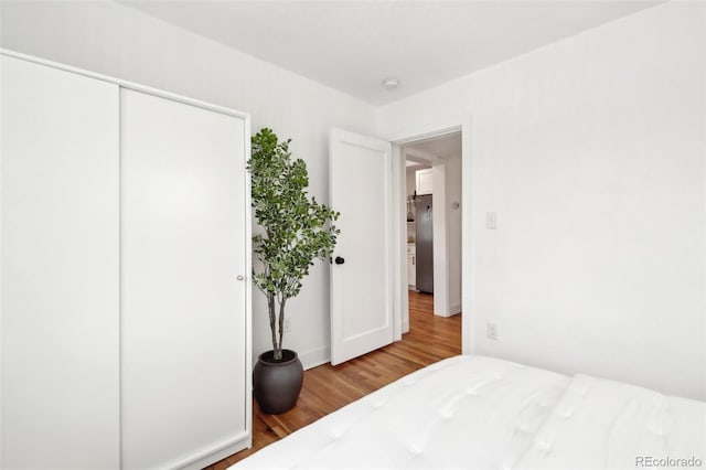 bedroom featuring hardwood / wood-style floors, a closet, and stainless steel refrigerator