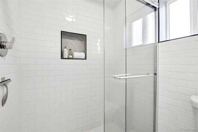 bathroom featuring toilet and a shower with shower door