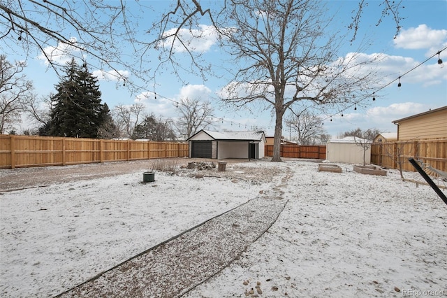 yard layered in snow featuring a storage shed and a garage