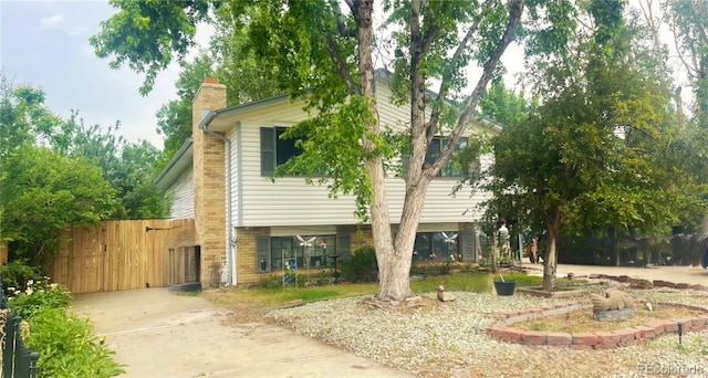 view of side of property with a gate and a chimney