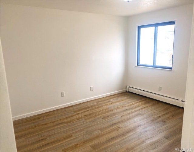 spare room with baseboards, baseboard heating, and wood finished floors