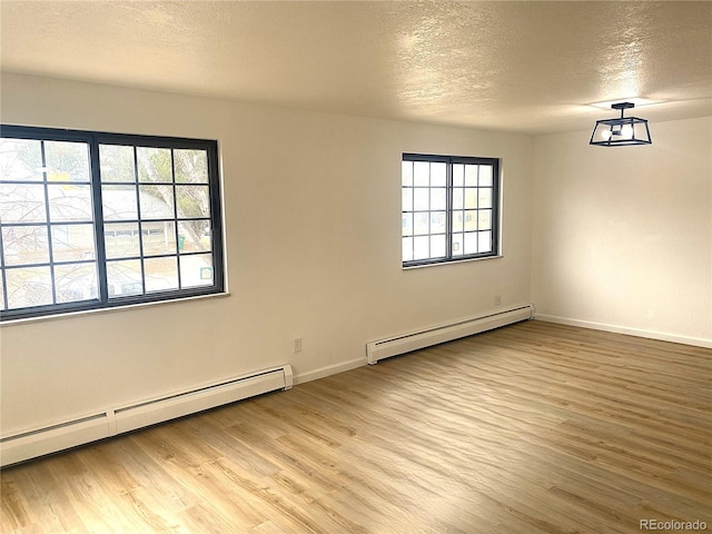 empty room featuring light wood finished floors, a textured ceiling, baseboards, and a baseboard radiator