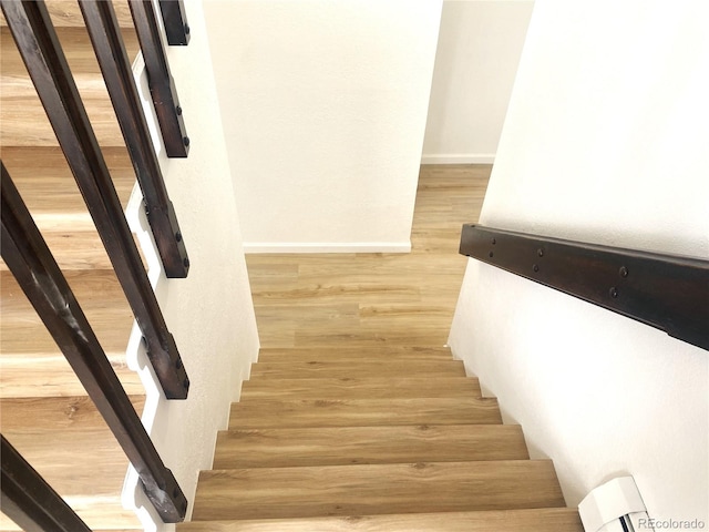 staircase featuring baseboards and wood finished floors