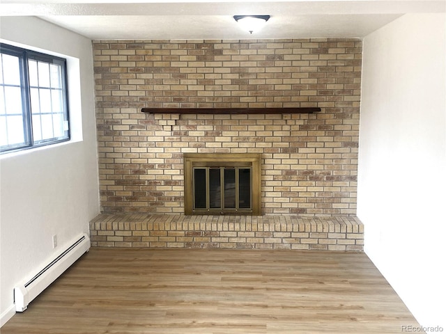 room details featuring a fireplace, a baseboard heating unit, and wood finished floors