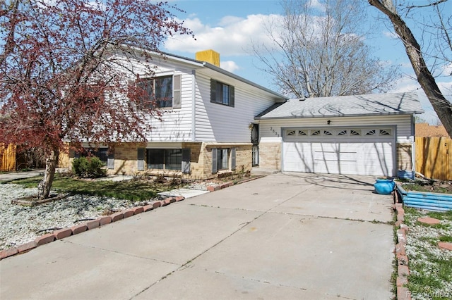 view of front of home with a garage, a chimney, fence, brick siding, and driveway