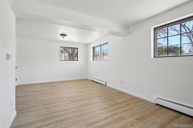 spare room featuring baseboards, light wood-style floors, and baseboard heating